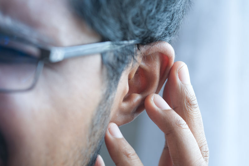 A man with ear and hearing issues touches his ear.