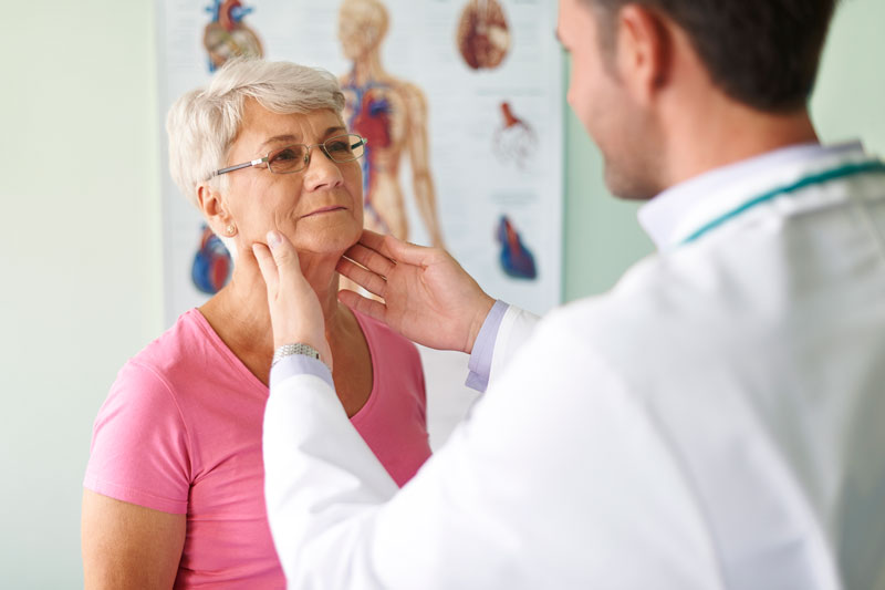 A woman’s primary care provider examines her neck and throat area.