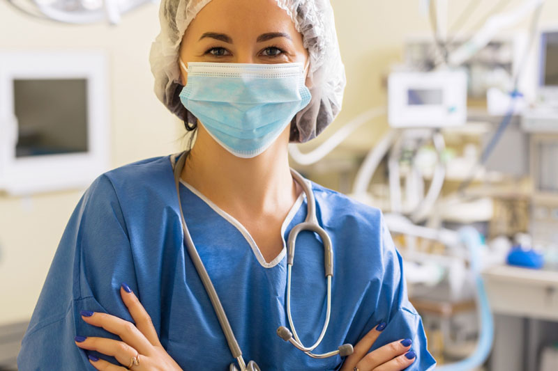 A general surgeon smiles behind her medical mask in a hospital setting.