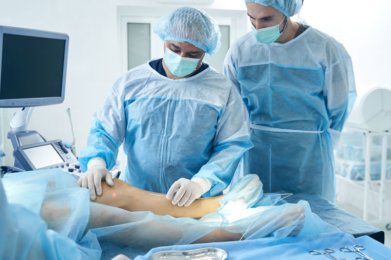 Vascular surgeons attend to a patient’s leg in a medical setting.