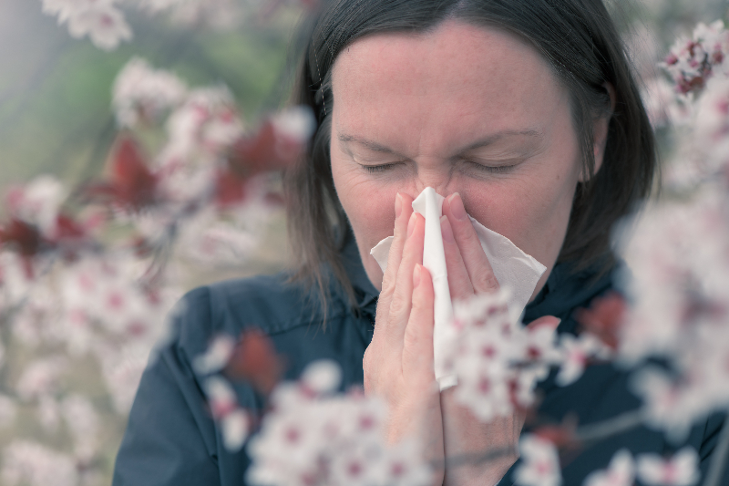 Woman with allergies blows her nose outside in Kansas City, Missouri.